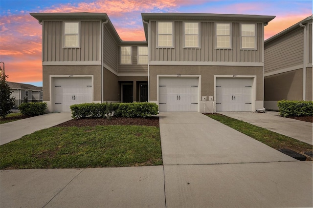 townhome / multi-family property featuring board and batten siding, concrete driveway, an attached garage, and stucco siding