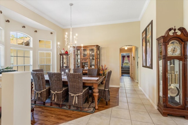 dining area with arched walkways, crown molding, an inviting chandelier, and light tile patterned floors