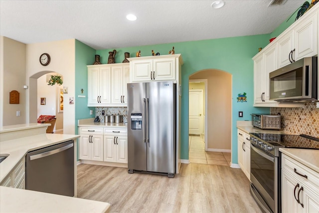 kitchen featuring appliances with stainless steel finishes, arched walkways, and decorative backsplash