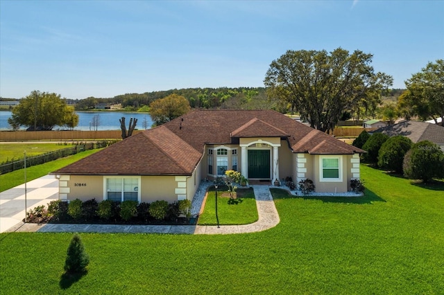 view of front facade with a shingled roof, a front yard, a water view, and stucco siding