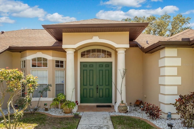 doorway to property with a shingled roof and stucco siding