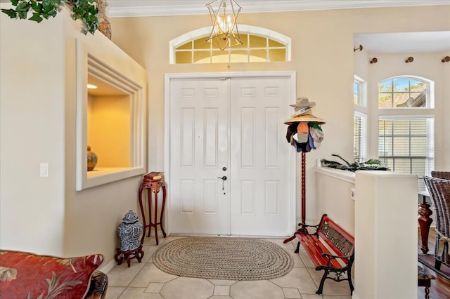 entrance foyer with light tile patterned floors, ornamental molding, and a notable chandelier