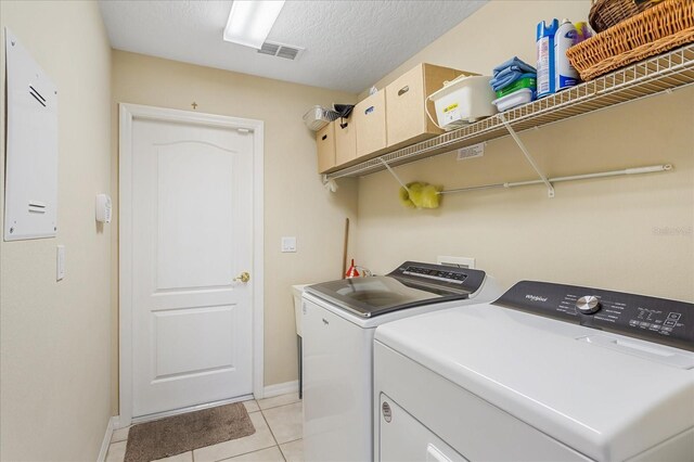 laundry area featuring laundry area, light tile patterned floors, visible vents, independent washer and dryer, and a textured ceiling