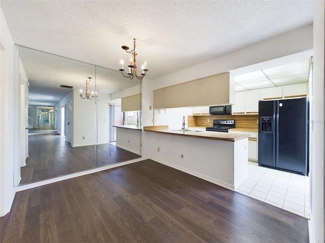 kitchen featuring a notable chandelier, white cabinets, open floor plan, light countertops, and black appliances