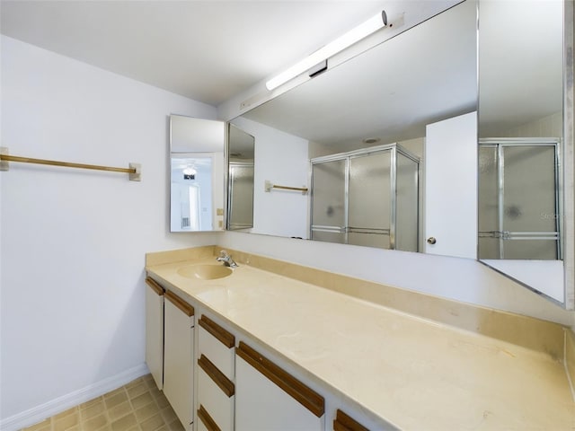 full bathroom with baseboards, an enclosed shower, and vanity