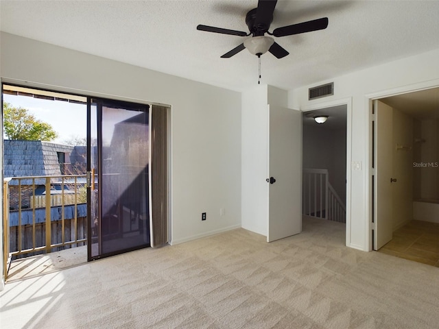 spare room with light carpet, visible vents, and a textured ceiling