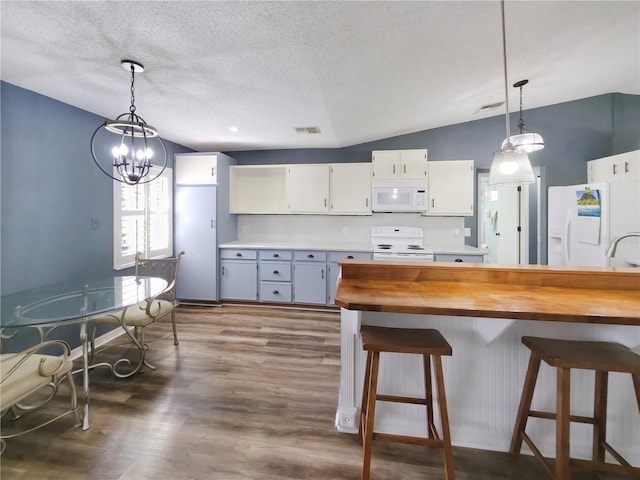 6106 Kittiwake Dr, Lakeland, FL 33809 - kitchen with decorative light fixtures, visible vents, white appliances, and dark wood-type flooring