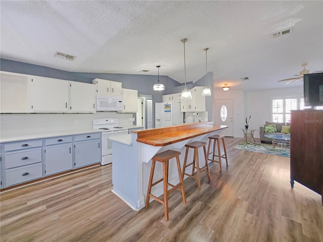 6106 Kittiwake Dr, Lakeland, FL 33809 - kitchen with visible vents, white appliances, light wood-style floors, and a kitchen breakfast bar