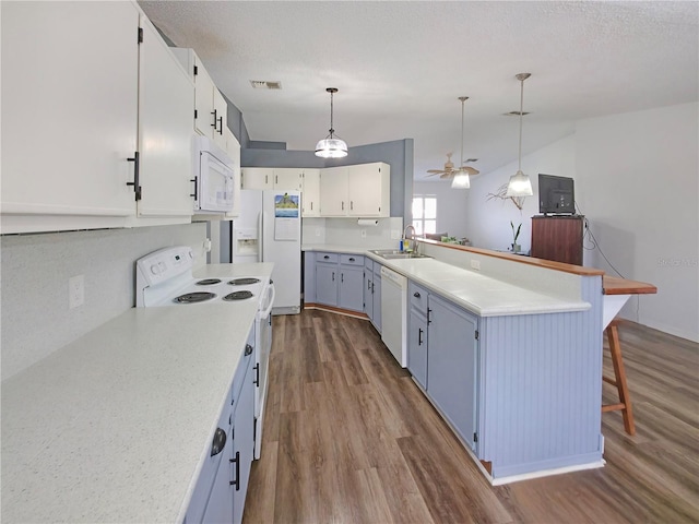 6106 Kittiwake Dr, Lakeland, FL 33809 - kitchen featuring white appliances, visible vents, dark wood finished floors, a peninsula, and a sink