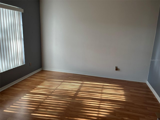 empty room with baseboards and wood finished floors