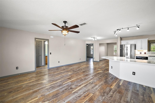 kitchen featuring dark wood-style flooring, light countertops, visible vents, freestanding refrigerator, and white cabinets