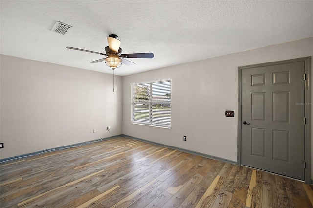 unfurnished room featuring visible vents, a ceiling fan, a textured ceiling, wood finished floors, and baseboards