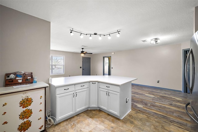 kitchen with freestanding refrigerator, a peninsula, light countertops, a textured ceiling, and white cabinetry