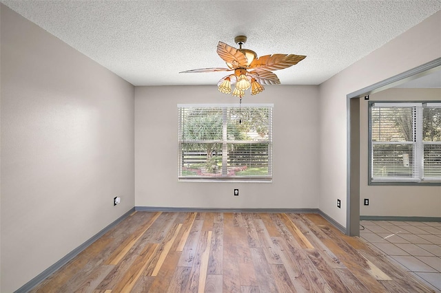 empty room with light wood-type flooring, a textured ceiling, and baseboards