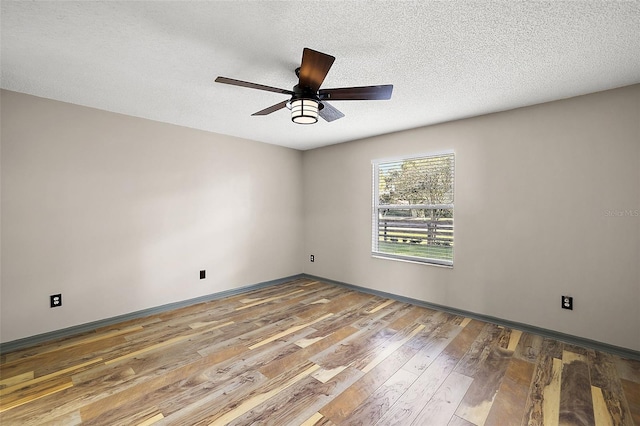 empty room featuring a textured ceiling, wood finished floors, a ceiling fan, and baseboards