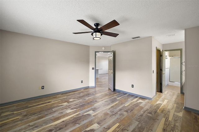 unfurnished bedroom with dark wood-style flooring, visible vents, ceiling fan, a textured ceiling, and baseboards