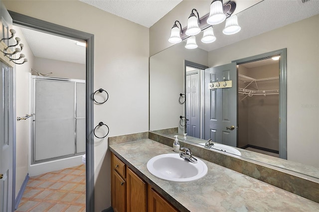 full bath featuring a spacious closet, toilet, a stall shower, a textured ceiling, and vanity