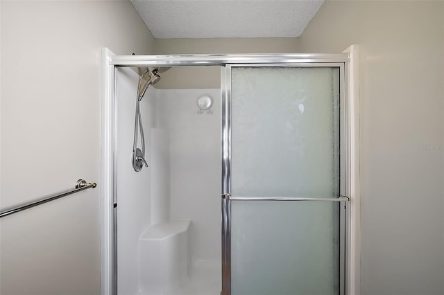 full bath with a shower stall and a textured ceiling