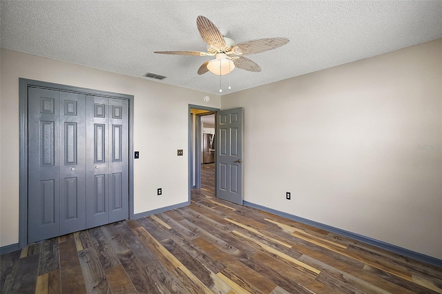 unfurnished bedroom featuring a textured ceiling, dark wood-style flooring, visible vents, and baseboards