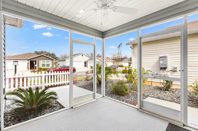 sunroom with a ceiling fan and a residential view