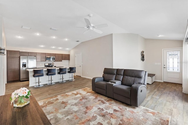 living area featuring lofted ceiling, ceiling fan, baseboards, and light wood-style floors