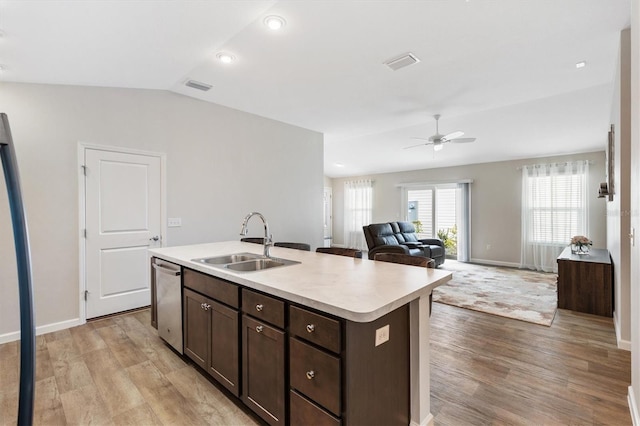 kitchen with a sink, visible vents, open floor plan, light countertops, and a center island with sink