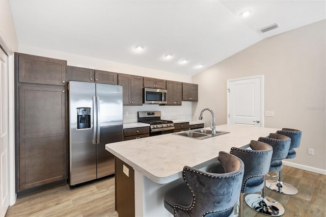 kitchen featuring a center island with sink, appliances with stainless steel finishes, a breakfast bar, light countertops, and a sink