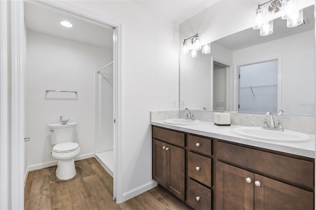 bathroom featuring double vanity, wood finished floors, a sink, and toilet