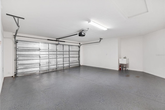 garage featuring a garage door opener, a sink, and baseboards