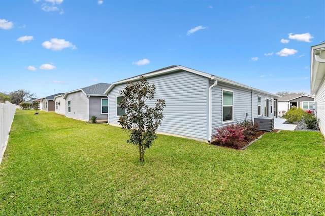 exterior space featuring a residential view, fence, a lawn, and central air condition unit