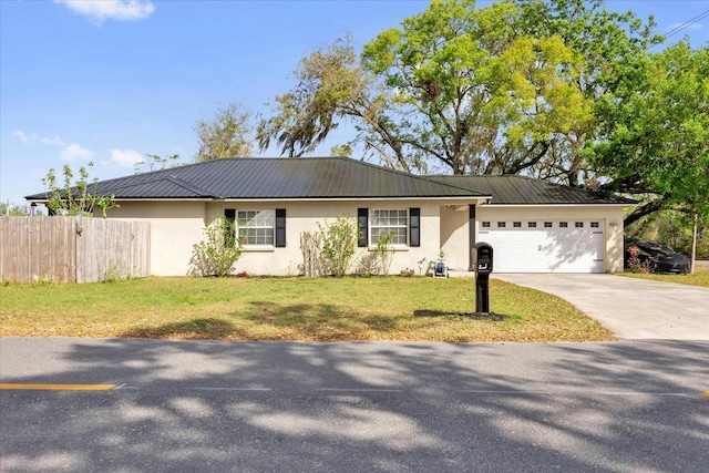 ranch-style home featuring a garage, concrete driveway, metal roof, fence, and stucco siding