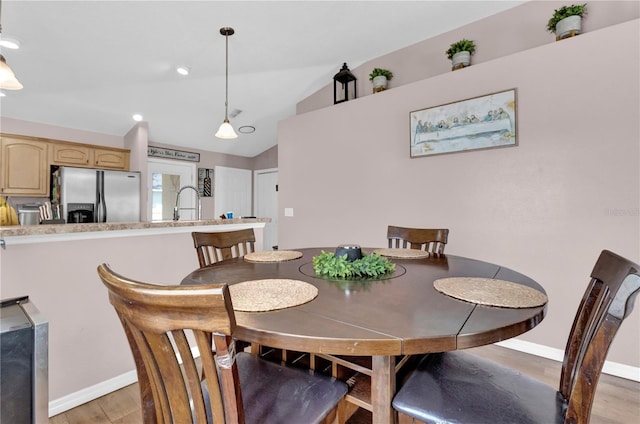 dining area featuring lofted ceiling, light wood-style floors, and baseboards