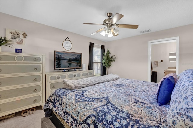 carpeted bedroom with a ceiling fan, visible vents, and ensuite bath