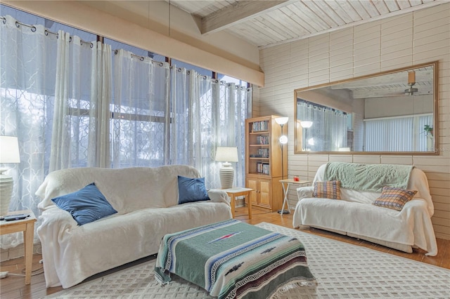 living room with wood walls, wood finished floors, and beam ceiling