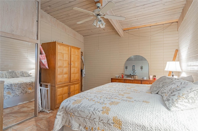 bedroom featuring ceiling fan, beam ceiling, wooden ceiling, and tile walls