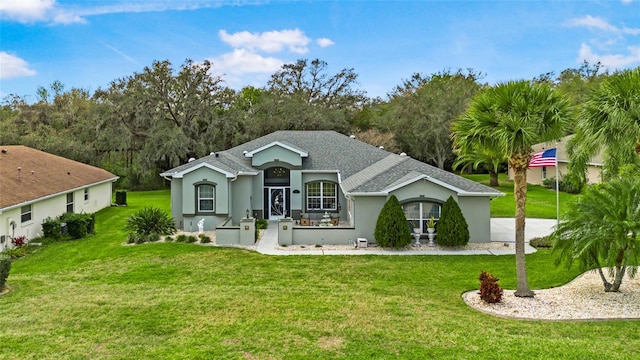 view of front of home with roof with shingles, a front lawn, and stucco siding