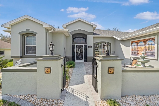 single story home featuring a shingled roof, a gate, a fenced front yard, and stucco siding