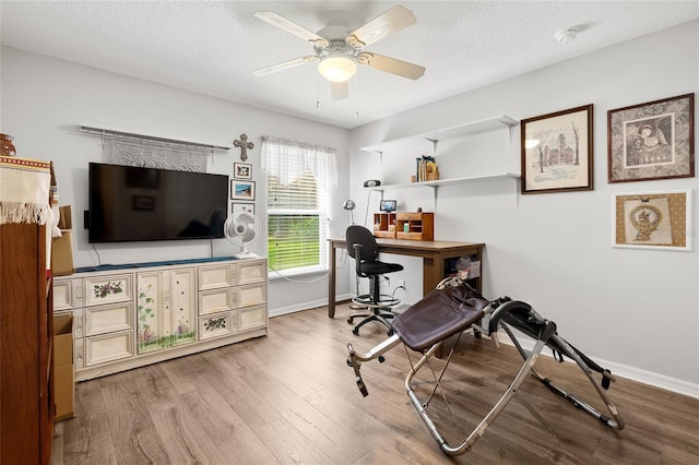 office area featuring a ceiling fan, a textured ceiling, baseboards, and wood finished floors