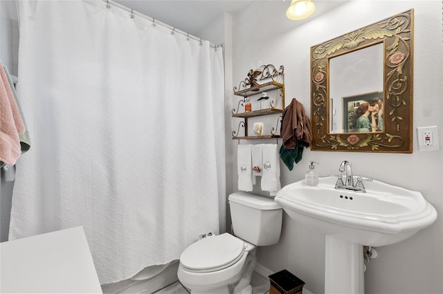 full bath featuring a shower with shower curtain, a sink, and toilet