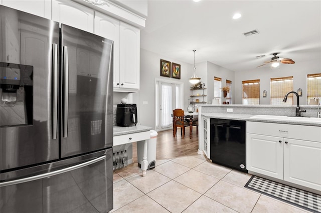 kitchen with black dishwasher, light tile patterned floors, visible vents, freestanding refrigerator, and a sink