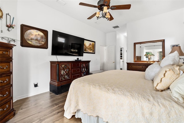 bedroom with a ceiling fan, baseboards, visible vents, and wood finished floors