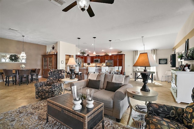 living area with visible vents, ceiling fan, and light tile patterned floors