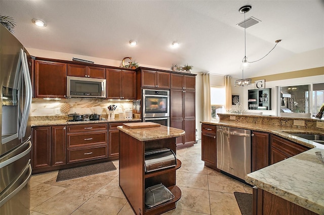 kitchen with stainless steel appliances, vaulted ceiling, hanging light fixtures, backsplash, and light stone countertops