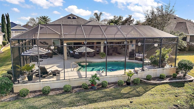 outdoor pool featuring glass enclosure, a patio area, and a yard