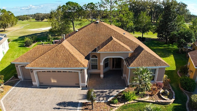 view of front of house featuring a garage, decorative driveway, roof with shingles, and stucco siding