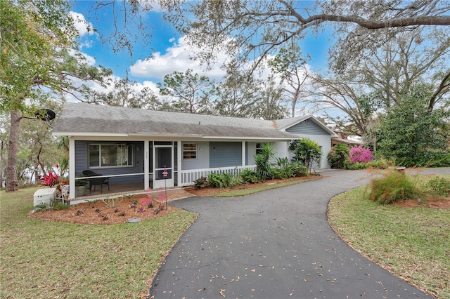 ranch-style home featuring aphalt driveway, a porch, and a front yard