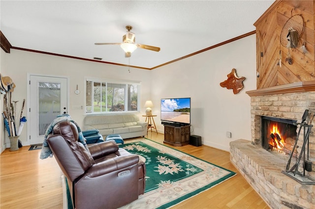 living room with baseboards, visible vents, ornamental molding, light wood-type flooring, and a fireplace