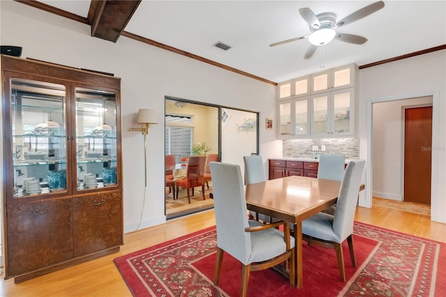 dining area with light wood finished floors, ornamental molding, and visible vents