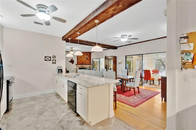 kitchen with visible vents, a breakfast bar, a peninsula, black appliances, and beam ceiling