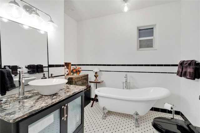 full bath featuring a freestanding bath, wainscoting, vanity, and tile walls